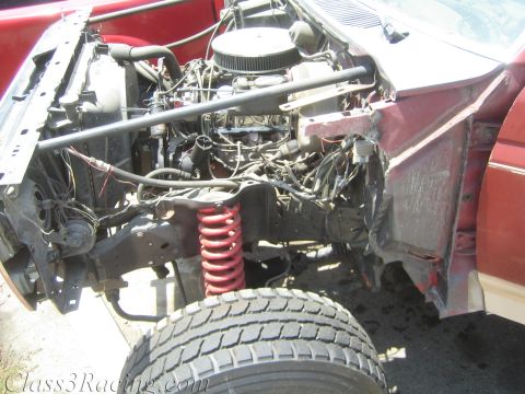1990 Ford Bronco - open engine bay of a red project truck reveals a V8 with chrome air cleaner and a red coilover spring over the front suspension.