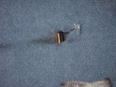 1994 Ford Bronco - A close-up shot shows a tear in the blue carpet, revealing a connector and wiring underneath.