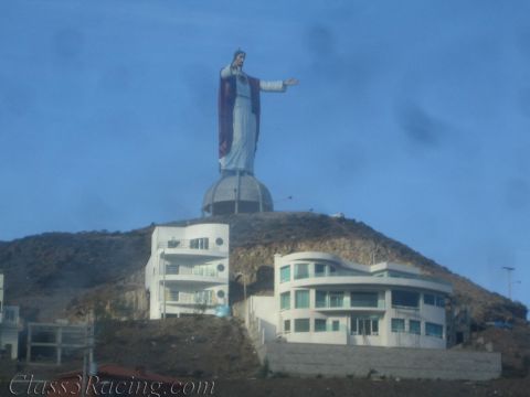 1990 Ford Bronco - large hilltop statue of Christ with outstretched arms overlooks a cluster of white multi-story buildings on a dry hillside.