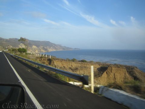 1990 Ford Bronco - View from a moving vehicle along a coastal highway, with a metal guardrail, eroded cliffs, and the ocean stretching toward distant headland…