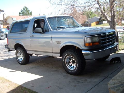 1994 Ford Bronco - This Ford Bronco is parked on a concrete driveway with a tree and houses in the background.