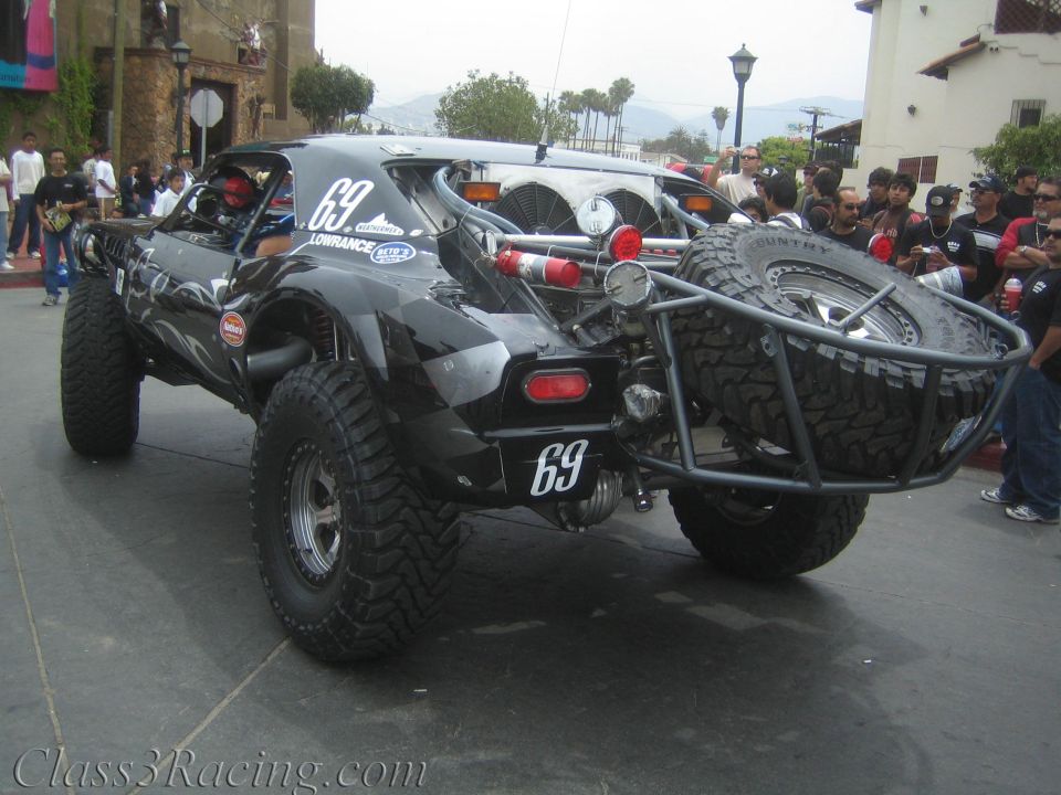 Rear view of black tube-frame off-road race buggy number 69 with spare tire mount