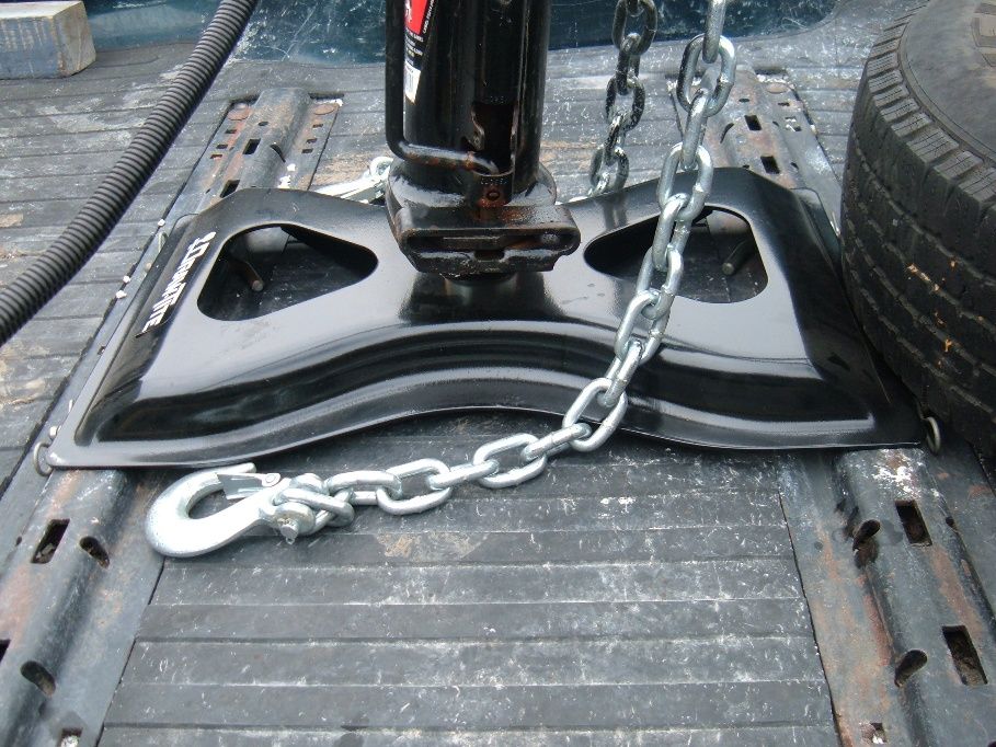 Fifth wheel trailer hitch assembly with chains attached, resting on a truck bed