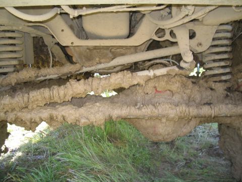 1989 Ford Bronco - The undercarriage of a vehicle is heavily coated in mud, obscuring details of its make and model.