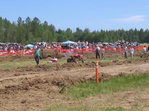 1989 Ford Bronco - Spectators watch ATVs navigate a muddy track during an outdoor event.