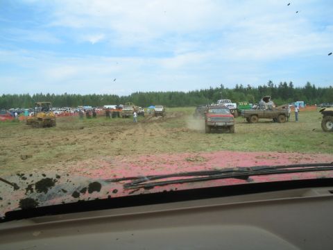 1989 Ford Bronco - Muddy field with several trucks and a bulldozer under a cloudy sky.