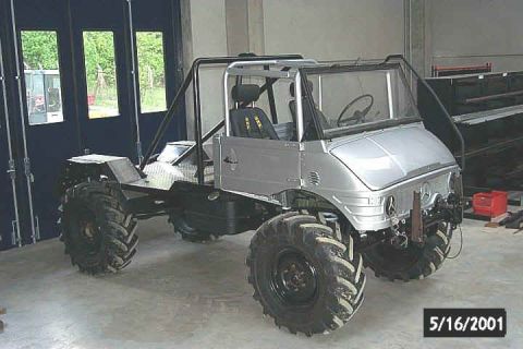 1991 Ford Bronco - A modified Mercedes-Benz Unimog with oversized tires and a roll cage sits in a workshop.