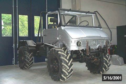 1991 Ford Bronco - Unimog chassis with large tires and roll cage, parked indoors.