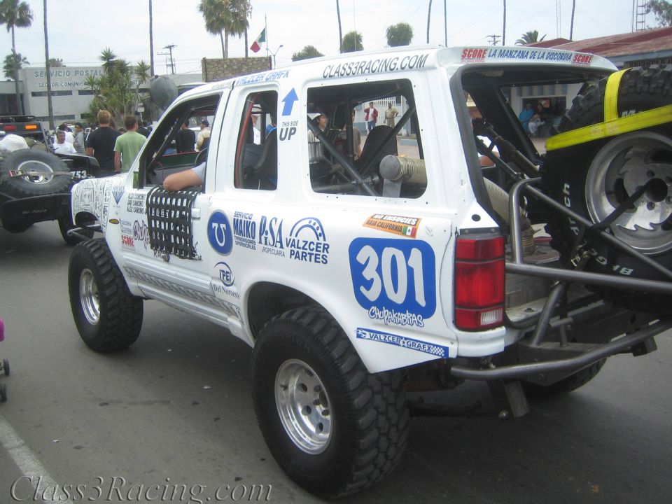 White Ford Explorer off-road race truck numbered 301 with spare tire on rear
