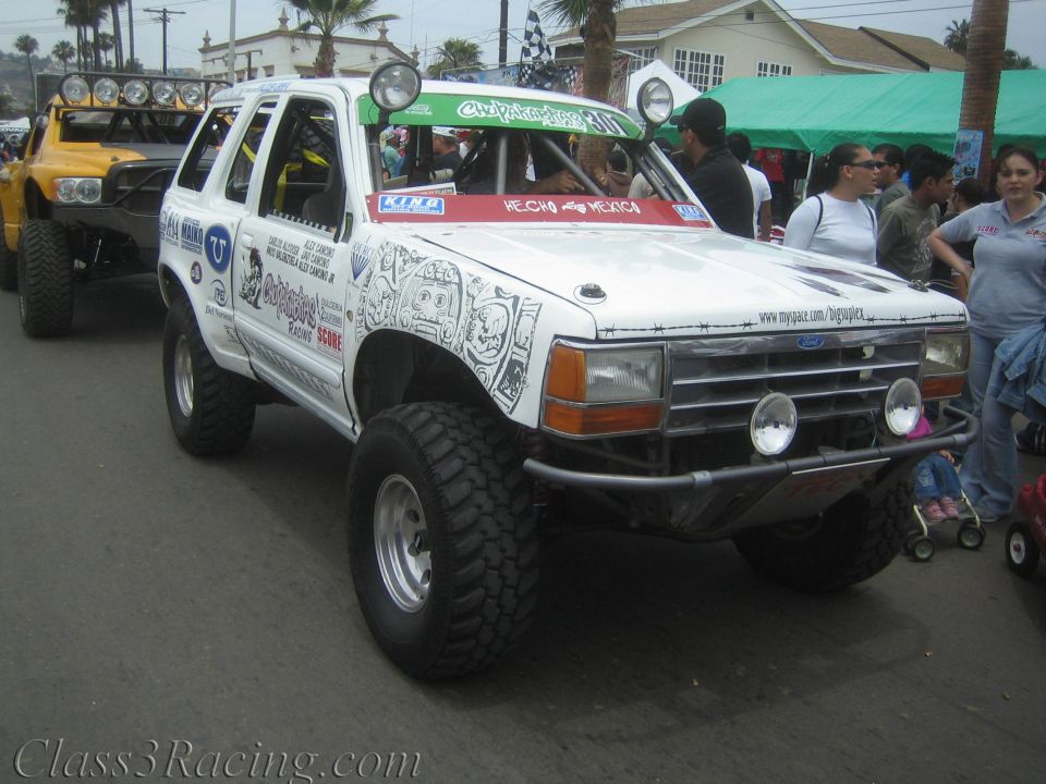 White Ford Explorer off-road race truck with roof light bar and graffiti-style art