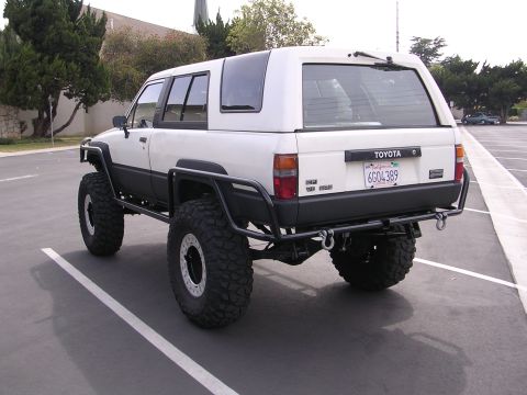 1985 Toyota 4Runner - Modified white Toyota 4Runner with large tires and custom bumpers is seen from the rear.