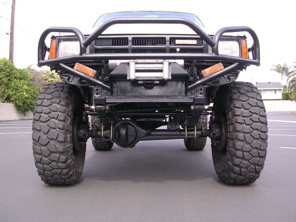 Front view of a modified 1984 Toyota 4Runner with large off-road tires, a winch, and a custom bumper