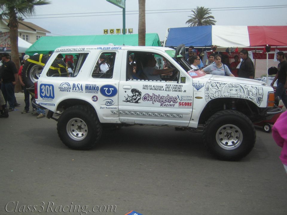 White Ford Explorer race truck numbered 301 in profile at a street event