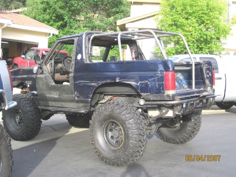 1994 Ford Bronco - Customized Ford Bronco with a roll cage and off-road tires, parked in a driveway.