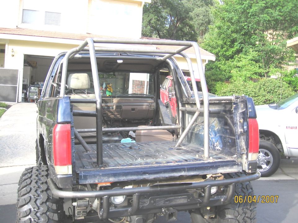 Rear of lifted blue Ford SUV with tube roll cage and stripped bare floor