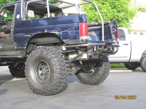 1994 Ford Bronco - Rear view of a heavily modified Ford Bronco, showing custom roll cage and off-road tires.