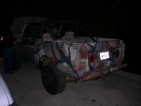 1994 Ford Bronco - This camouflaged SUV, likely a 1978 model, is viewed from the rear, showing its roll cage and rusty bumper.