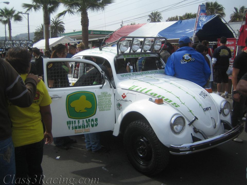 White off-road Volkswagen Beetle race car with Villanos graphics and roof light bar