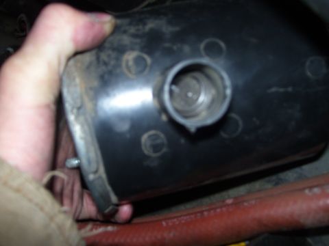 1986 Ford Bronco - A person is holding a black automotive component with a metal threaded fitting.
