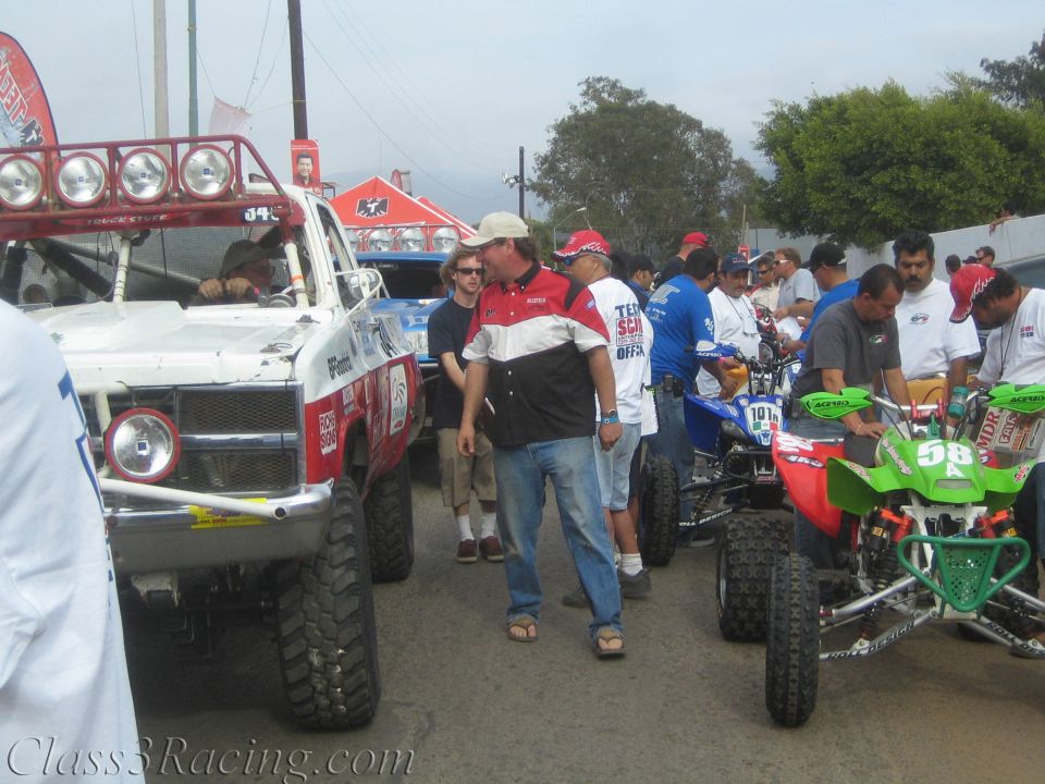 Crowd of people between off-road race trucks and ATVs on a street