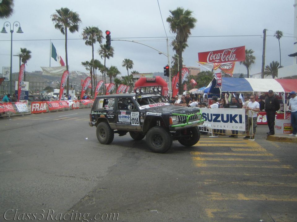 Black-and-green Jeep Cherokee race vehicle number 1705 at a street start with Suzuki banner
