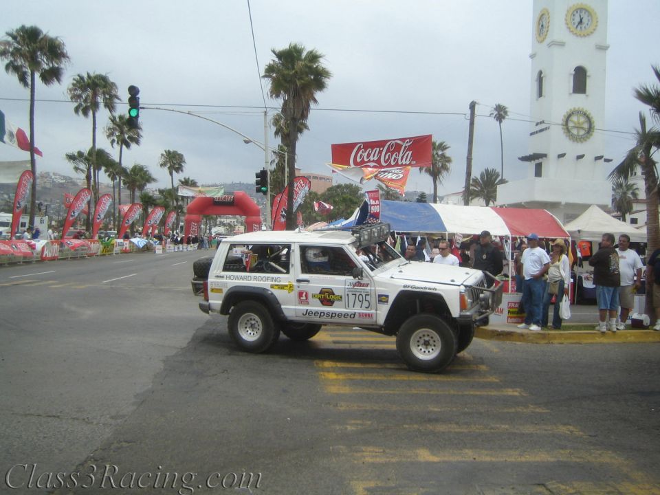 White Jeep Cherokee race vehicle number 1795 with Jeepspeed livery at a street start near clock tower
