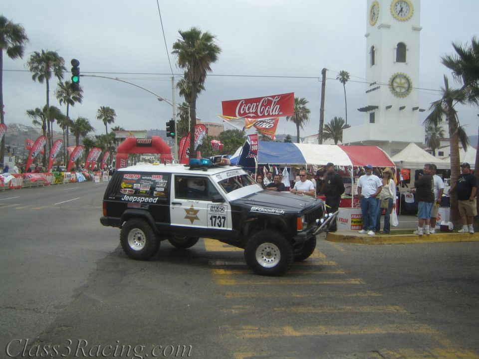 Black-and-white Jeep Cherokee race vehicle number 1737 styled like a police car at a street start