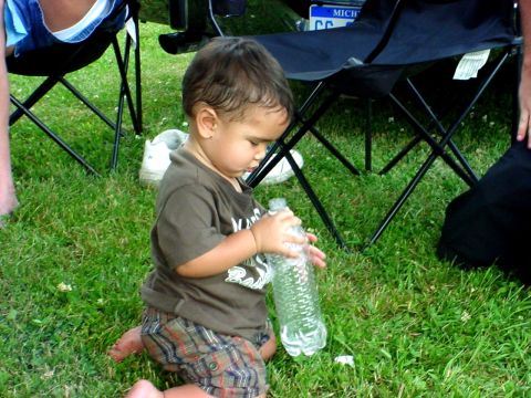 1992 Ford Mustang - A young child plays with a water bottle on a grassy lawn, with chairs and a license plate in the background.