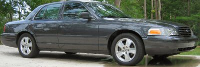 1985 Ford LTD Crown Victoria - A dark gray sedan is parked outdoors, viewed from the front quarter angle.