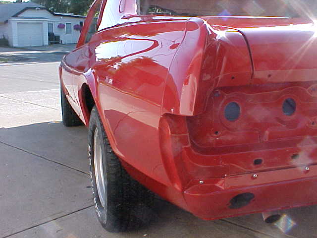 Red 1967 Mercury Cougar rear quarter panel, showing exposed metal and tire