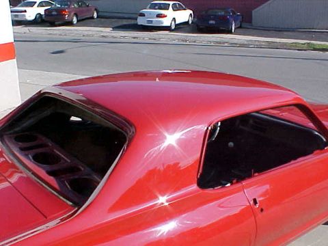 1967 Mercury Cougar - The interior of a red car is visible, with other vehicles parked behind it.