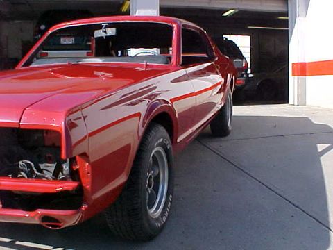 1967 Mercury Cougar - A red 1967 Mercury Cougar is partially visible in a garage, with its front end disassembled.