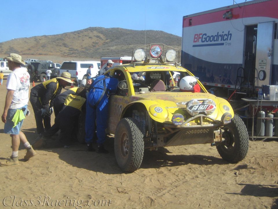 Crew services a yellow off-road buggy beside a BFGoodrich semi-trailer