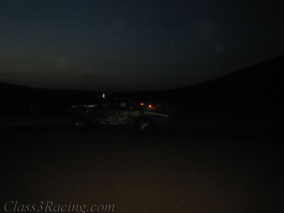 Distant off-road race truck at dusk with running lights on a dark course
