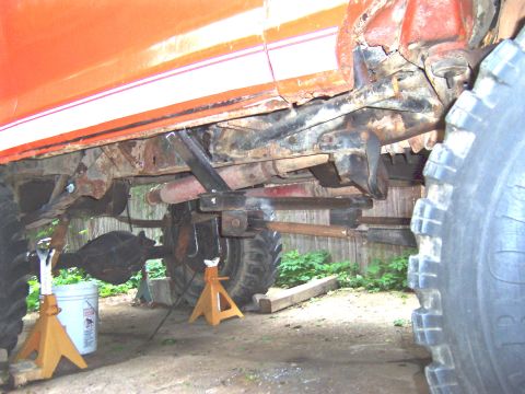 1978 Ford Bronco - Vehicle frame and suspension components are heavily rusted and supported by jack stands.