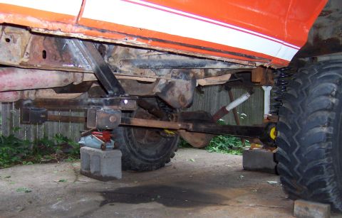 1978 Ford Bronco - The underside of a vehicle shows extensive modifications to the suspension system and large off-road tires.