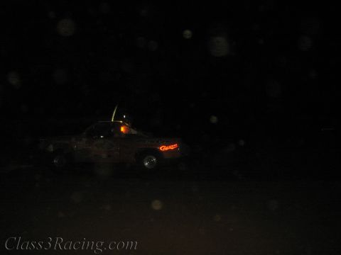 1990 Ford Bronco - dimly lit off-road race truck with small running lights moves across a very dark night course.