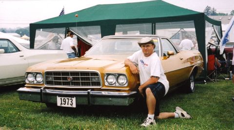 1979 Ford Ranchero - A man poses with a gold 1973 Ford Ranchero at an outdoor event.