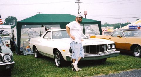 1979 Ford Ranchero - A man stands next to a white Ford Ranchero at an outdoor event with other vehicles present.