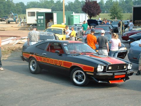 1978 Ford Mustang II - This 1976 Ford Mustang Cobra II features a distinctive black and orange paint scheme with prominent side decals.