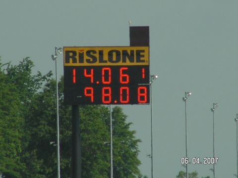 1988 Ford Mustang - A digital scoreboard displays race times and the Rislone logo against a hazy sky.