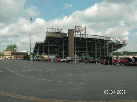 1988 Ford Mustang - A stadium and parking lot scene with multiple vehicles present on a cloudy day.