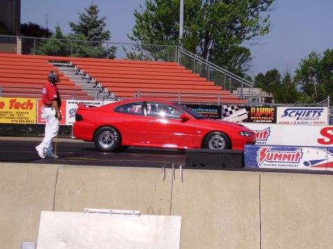 1988 Ford Mustang - Red coupe drag car at a drag strip, with spectator seating and sponsor banners visible.