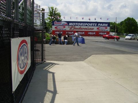 1988 Ford Mustang - Drag strip scene at Norwalk Motorsports Park with a red car and white van on the track.