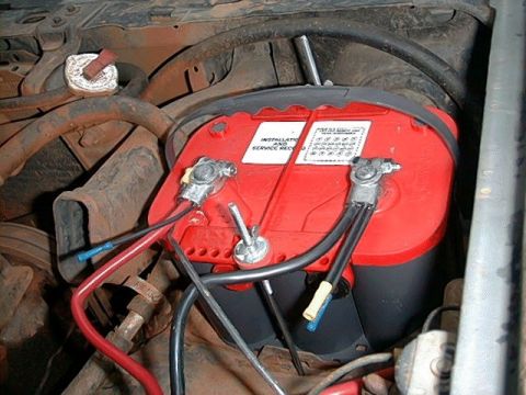 1980 Ford Bronco - Close-up of a car battery and its wiring in an engine bay.