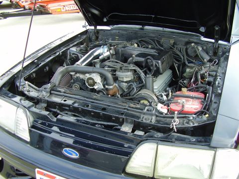 1988 Ford Mustang - The engine bay of a 1988 Ford Mustang shows a modified engine with custom intake piping and an intercooler.