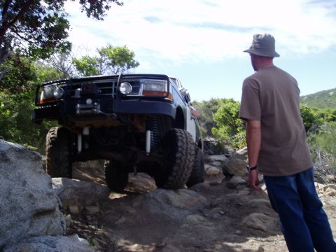 1994 Ford Bronco - This lifted 1994 Ford Bronco tackles a challenging rocky off-road course with its driver observing.