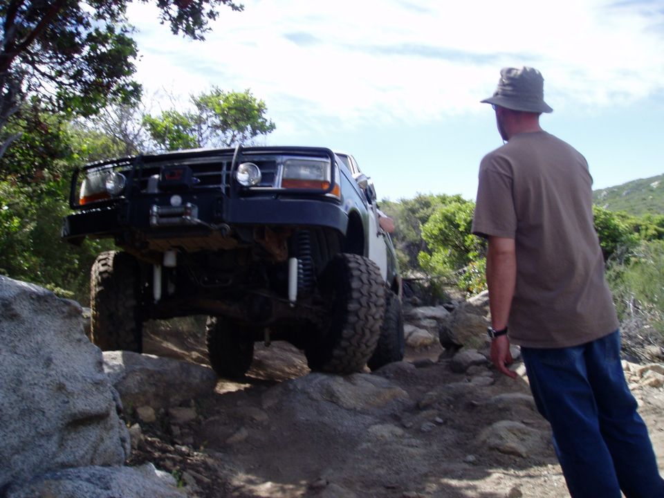 1994 Ford Bronco with lifted suspension and large tires navigating a rocky trail