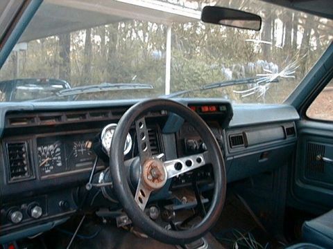 1980 Ford Bronco - Interior view of a 1980 Ford Bronco, showing the dashboard, steering wheel, and a cracked windshield.