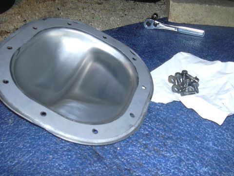 1996 Ford Crown Victoria - Differential cover and bolts are laid out on a blue surface next to a ratchet, ready for installation.